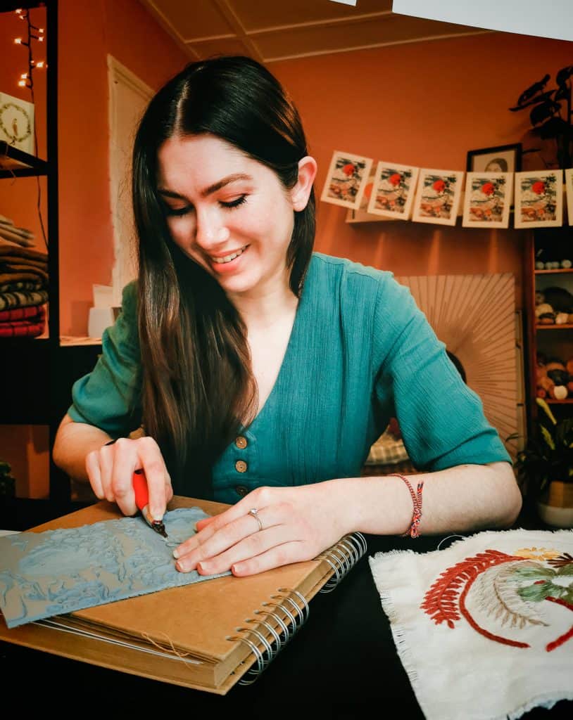 Portrait of a smiling artist carving vinyl for a screen print. Taken remotely